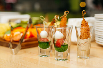 set of caprese canapes in shots, party snacks in glasses on a table in a cafe, appetizers and finger food