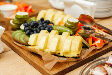 a wooden cutting board topped with assorted fruit, fruit pieces in a buffet table, close-up