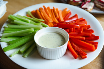 sliced vegetable sticks on a white plate with dipping sauce close up