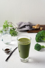 Healthy green smoothie in a glass with drinking straw made of broccoli and chia seeds on a white background