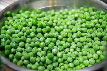 Green peas in a metal bowl on a market stall, close up - obrazy, fototapety, plakaty
