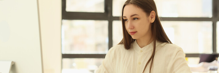 Young manager works at computer at her workplace.