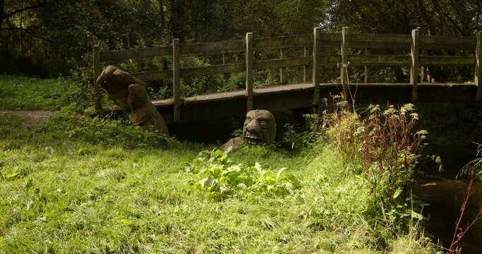 mid shot of wooden bridge over scow Brook with carved wooden troll man at bridge base