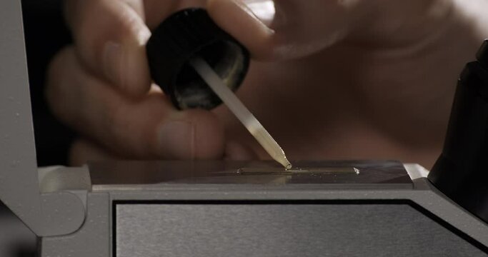 Gemstone laboratory. Specialist checks diamond or gem quality. Gemologist drops oil on the device to measure the refractive index of faceted stone. Diamond or gem grading and valuation