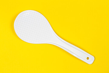 White plastic spatula on a yellow background. Plastic spatula for coated dishes.