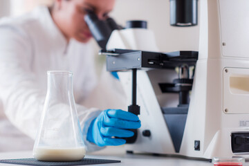 A quality control specialist inspects milk samples under a microscope in a lab