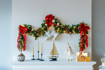 open wooden shelf with candles,dolls, presents, sea boat toy and Christmas decorations for the New Year holiday and Christmas. white wall
