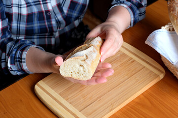 Hands of an elderly woman holding sliced white wheat bread baguette