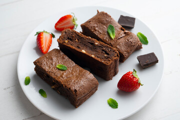 Chocolate brownie cut into portions and decorated with strawberries and mint.