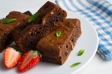 Chocolate brownie cut into portions and decorated with strawberries and mint.