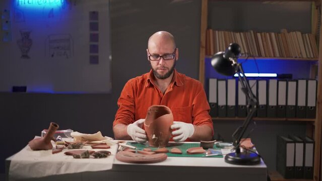 Archaeologist working in the office overtime at night. Study of ancient culture and civilization. Old clay amphora, ancient vessel. Excavation and archeology
