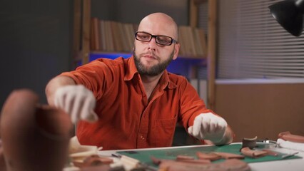 An archaeologist works late in the office with artifacts from an ancient culture. Excavation and archeology