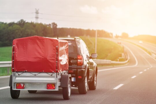 SUV with trailer goes on the highway. Moving stuff with a small rentable trailer.