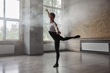 Confidence male ballet dancer practicing alone in studio room - obrazy, fototapety, plakaty
