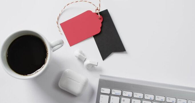 Video of computer keyboard, cup of coffee, earphones, gift tags with copy space on white background