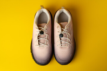 Beige sport running shoes on yellow studio background