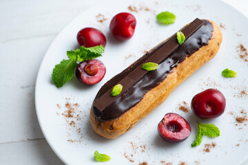Fototapeta na wymiar French eclairs filled with chocolate cream and served with fresh cherries.