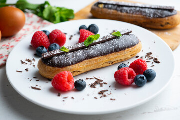 French eclairs filled with chocolate cream and served with wild berries.