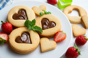Butter cookies with hearts filled with chocolate cream and strawberries.