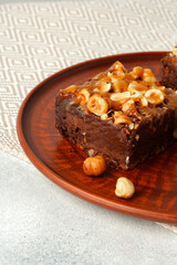 Brownie cake with nuts topping on plate close up