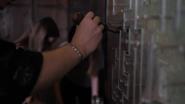 Close-up of a man driving a magnet along a glass wall with a maze, performing a task in a quest room. Dark scary room for a quest. Young people actively spend their free time.