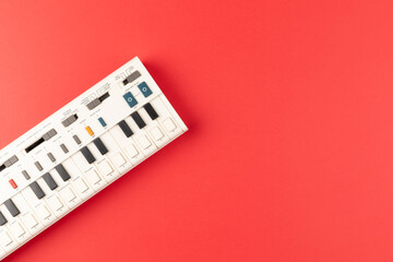 Vintage electronic keyboard synth piano on red background