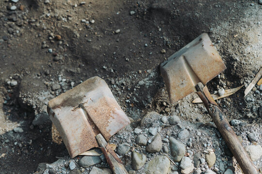 two shovels lying on the rocks and river sand