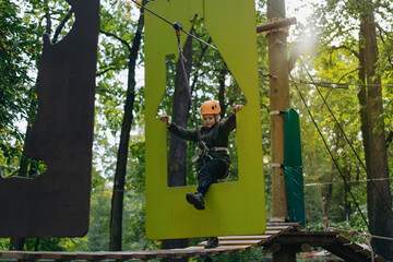 well equipped teenage boy in outdoor passing obstacle course. Active recreation in high rope park