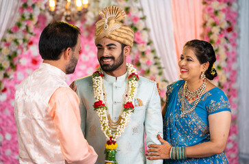 Happy Indian newlywed Couple or bride and groom posing to camera by holding eachother on wedding...