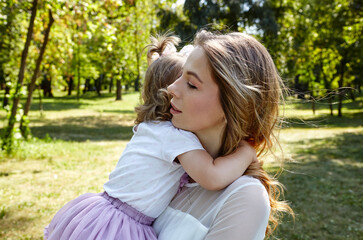 Mother and daughter walk in the summer city park. Childhood, leisure and people concept - happy family rest on nature and have a good time