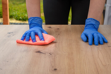 Kobieta ściera kurze z drewnianego stolika szmatką z mikrofibry