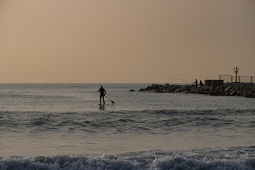 Fototapeta na wymiar amanecer en el espigón paddle surf surf con remo