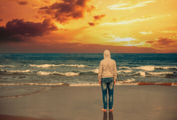 Young man stands on the beach in the evening. The man gazing magical sunset