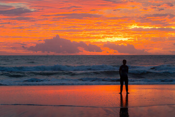 Fototapeta na wymiar silhouette man walk on beach,phoenix sky Twilight with gloomy clouds