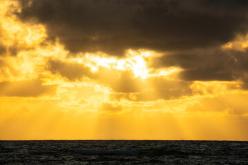 The sun's rays shine through the clouds, creating beautiful images above sea level.Beautiful, colorful, sunrise over the sea