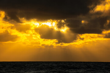 The sun's rays shine through the clouds, creating beautiful images above sea level.Beautiful, colorful, sunrise over the sea