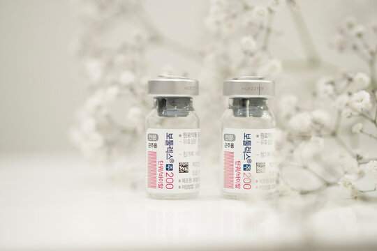 Two bottle of Botox, botulax toxin stands on a white table against a background with flowers. copy space for text. skin care concept . Ukraine, Kyiv 07.24 2023