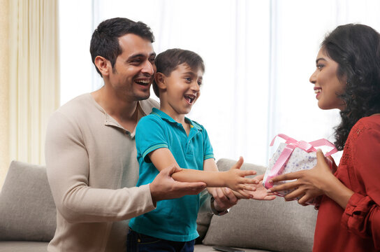 Father holding son while mother snatching gift 