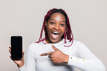 Delighted African American woman holding cellphone with black screen in hand pointing indicating...