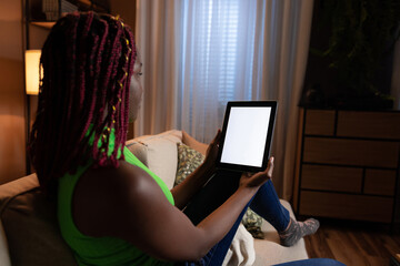 Happy avid reader, using her tablet to access her favorite books and read e-books in her living room white tablet mockup screen concept.