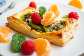 Puff pastry tartlet with pastry cream and kiwi decorated with fresh fruit.