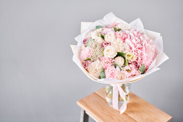 Beautiful bouquet of fresh flowers in glass vase on wooden table. A gift bouquet in mix color scheme for any holiday. The concept of a small flower shop. Flower and gift delivery