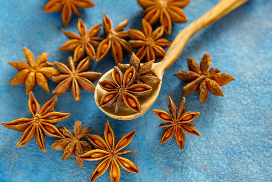 Star anise in a wooden spoon on an azure background