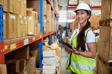 portrait worker working on tablet and looking at cardboard box on shelf in warehouse storage