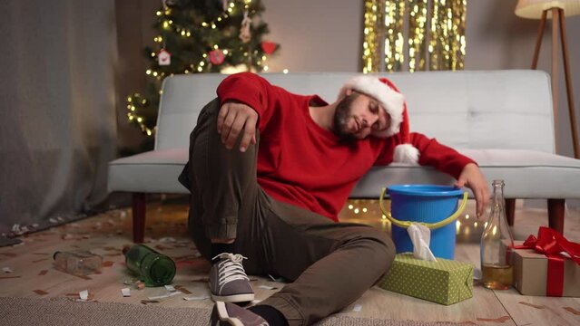 Hangover after a Christmas party at home. Young man suffering from nausea and vomiting.