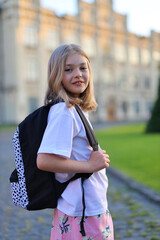 A young caucasian pupil, full of youthful charm, studies in the park, her backpack by her side.