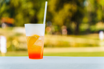 A glass with a refreshing summer cocktail on a blurred natural green background