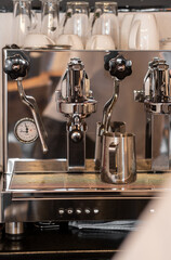 The barista prepares fresh coffee in the coffee machine in the morning in the cafe. There are coffee cups on the table for customers. Coffee machine close-up