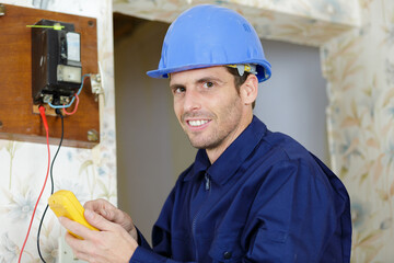 electrician using multimeter to test old fashioned electricity meter