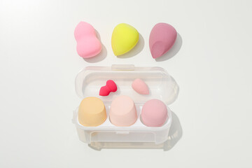 Cosmetic sponges in case on white background, top view